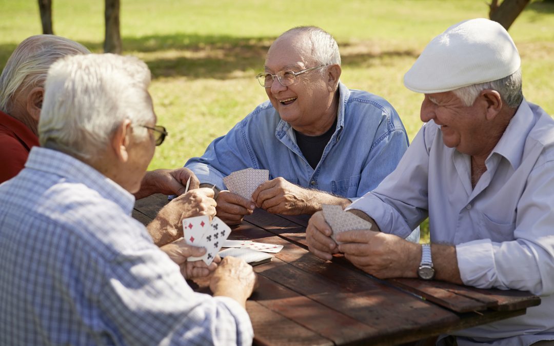 Seniors playing cards in a park. Many assisted living in Surprise AZ take their residents on field trips to the local park